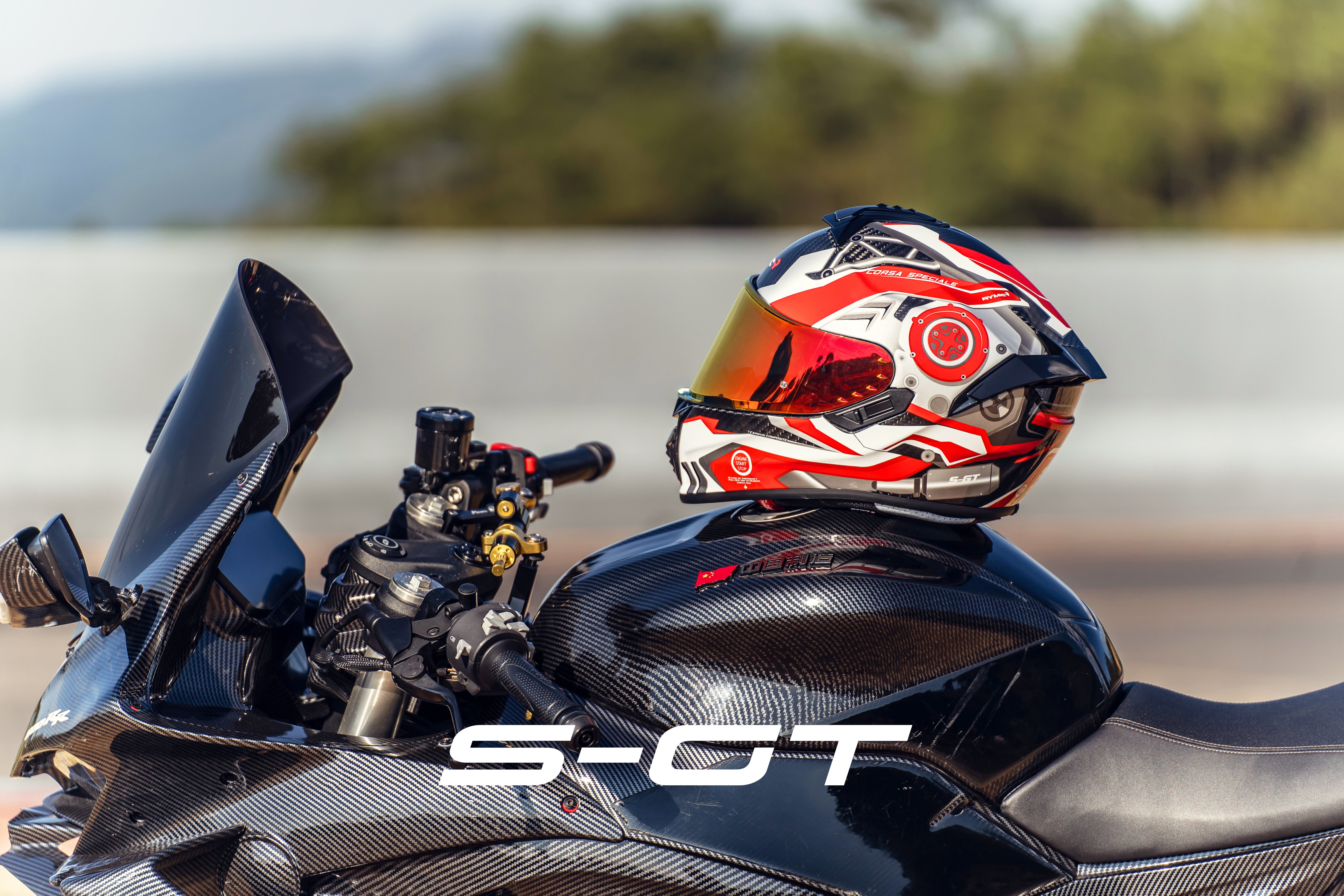 Mounted on a motorcycle, the RYMIC S-GT red & black full-face helmet highlights its sleek and aerodynamic profile.